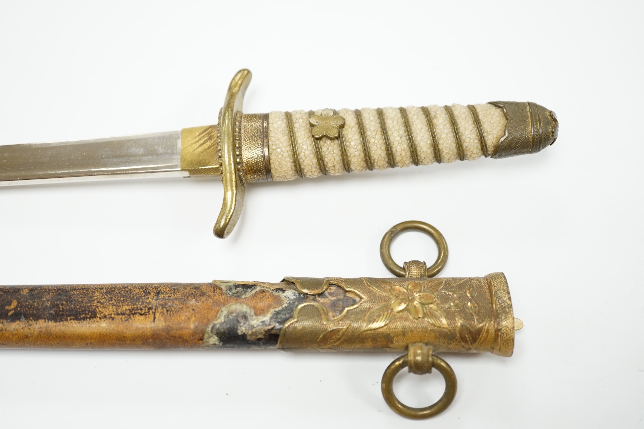 A dagger with brass fittings and a shagreen grip, in a leather covered scabbard, blade 21cm. Condition - losses to leatherwork and scabbard, splits to shagreen grip and some wear overall.
